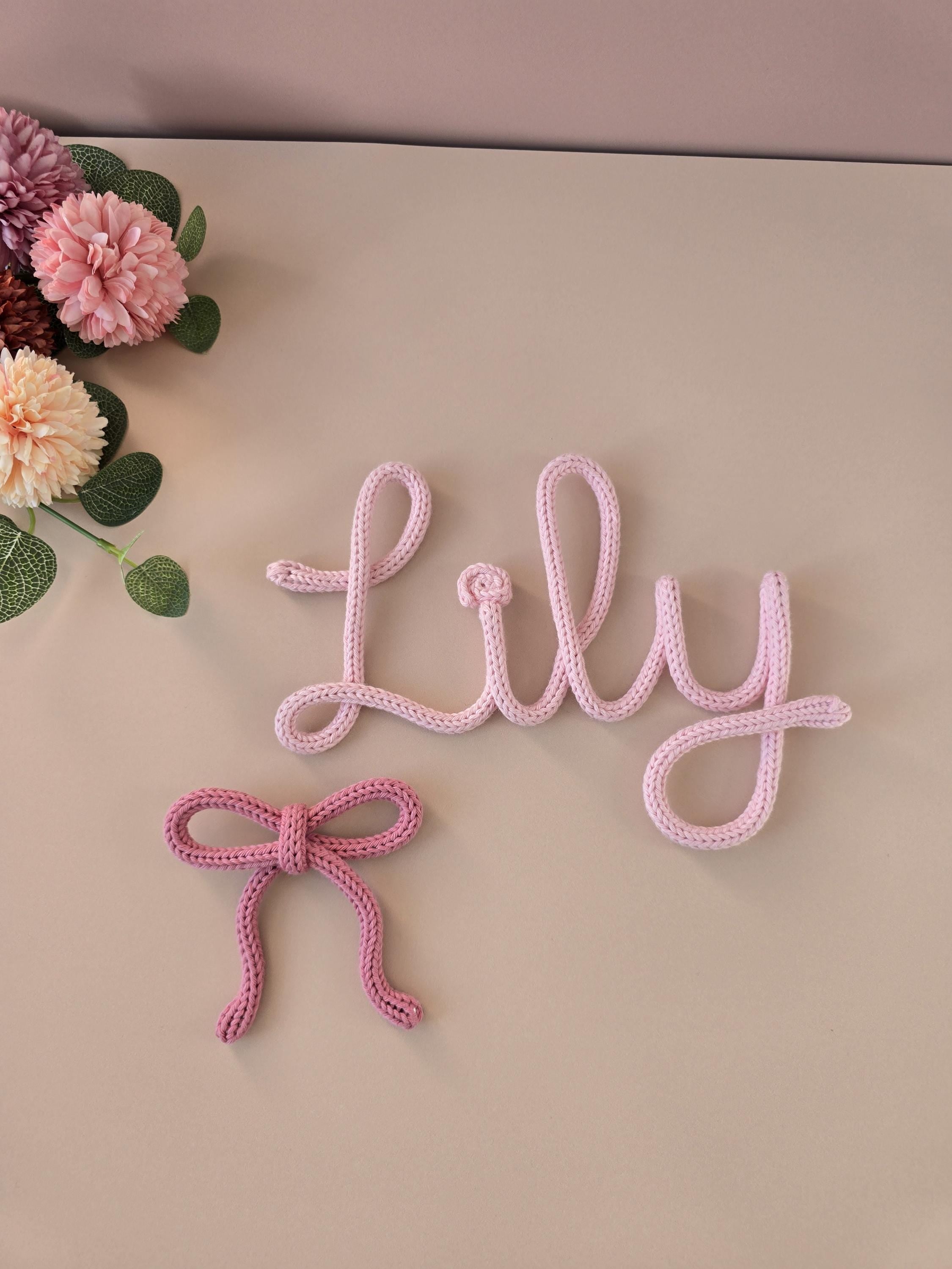 Pink decorative name 'Lily' with a bow on a beige background with flowers.