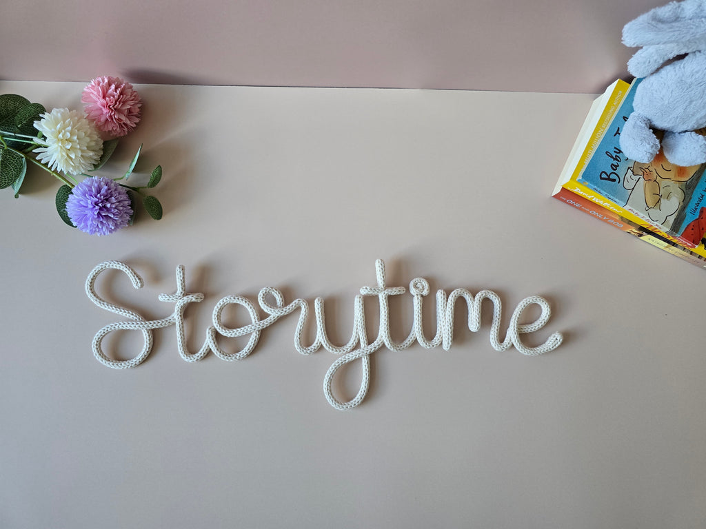 Decorative word 'Storytime' on a surface with flowers and a book in the background.