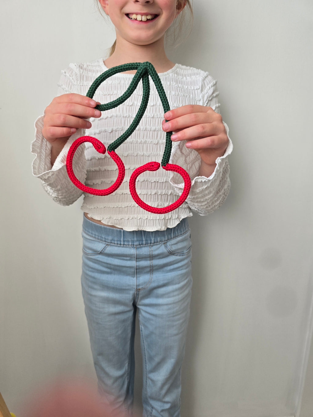 Child holding a handmade knitted wire cherry sign