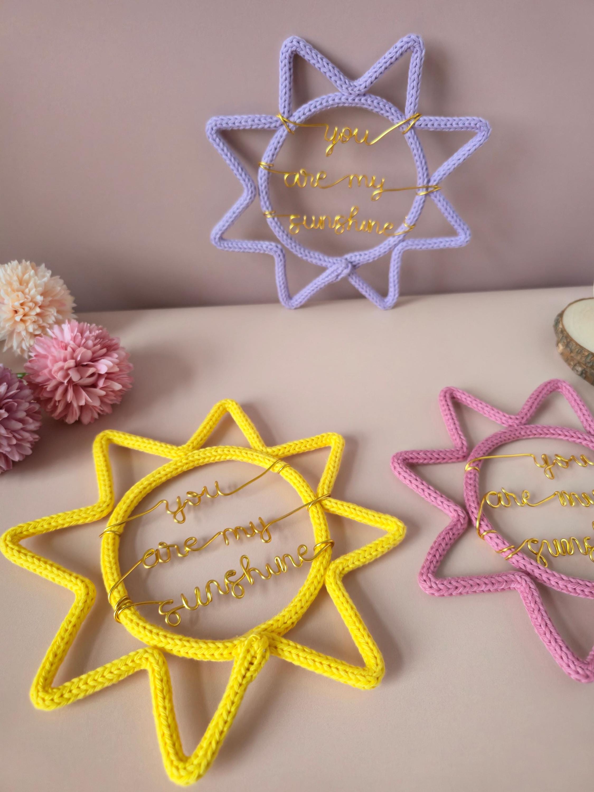 Star-shaped decorative items with embroidered text on a soft pink background