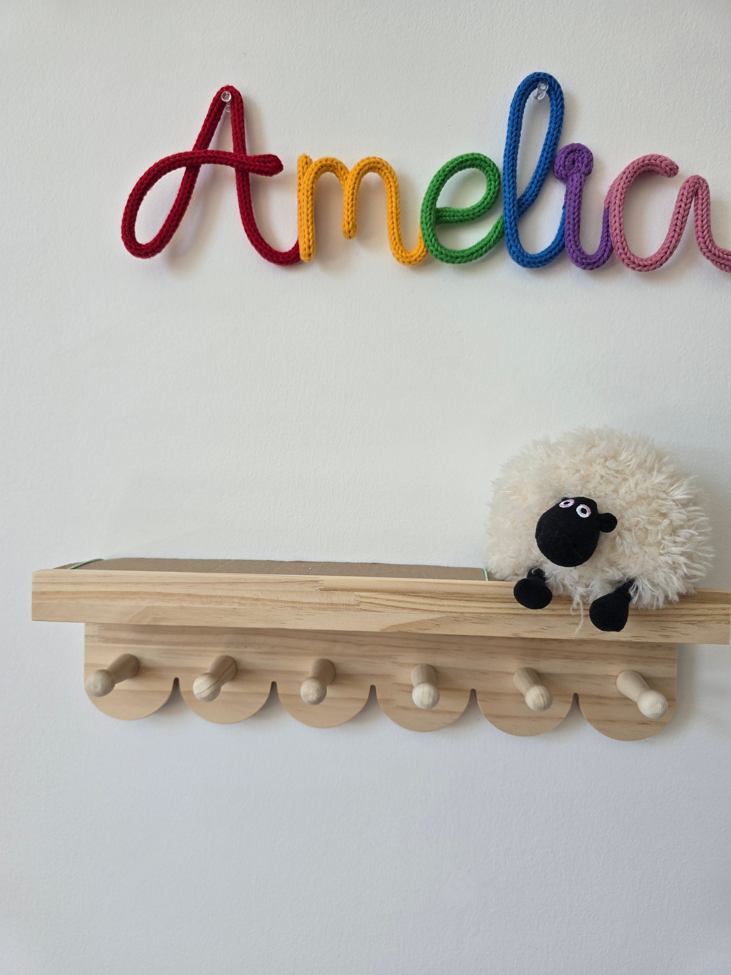 Rainbow personalised name sign reading Amelia displayed on a children’s bedroom wall above a wooden shelf.