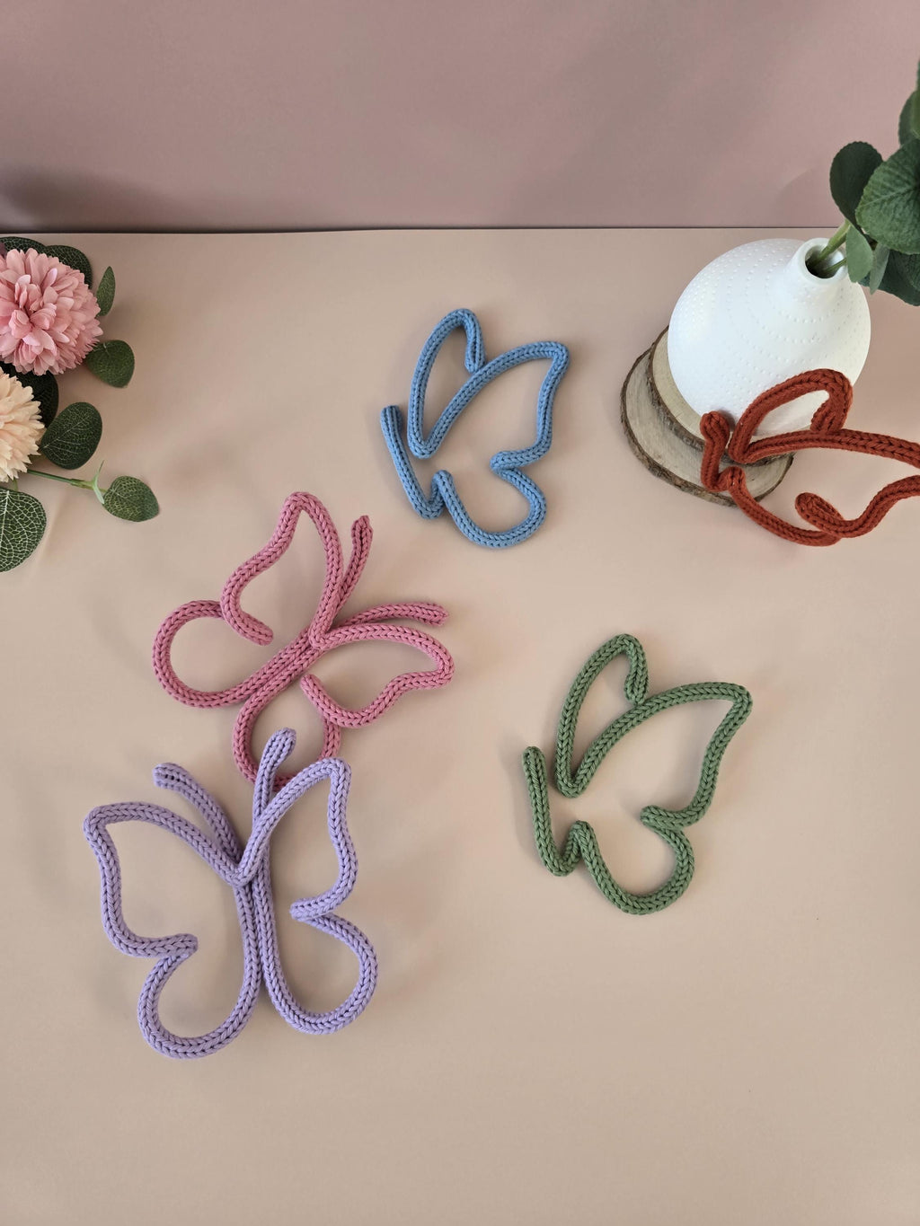 Colorful butterfly-shaped objects on a beige surface with a pink background