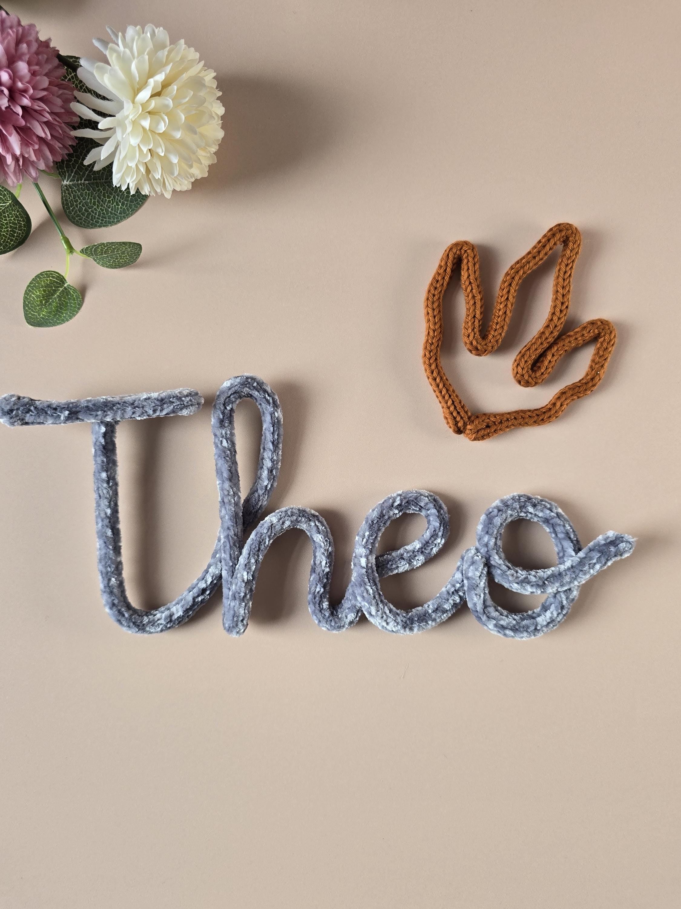 Knitted wire dinosaur decoration used as an add-on for a personalised name sign