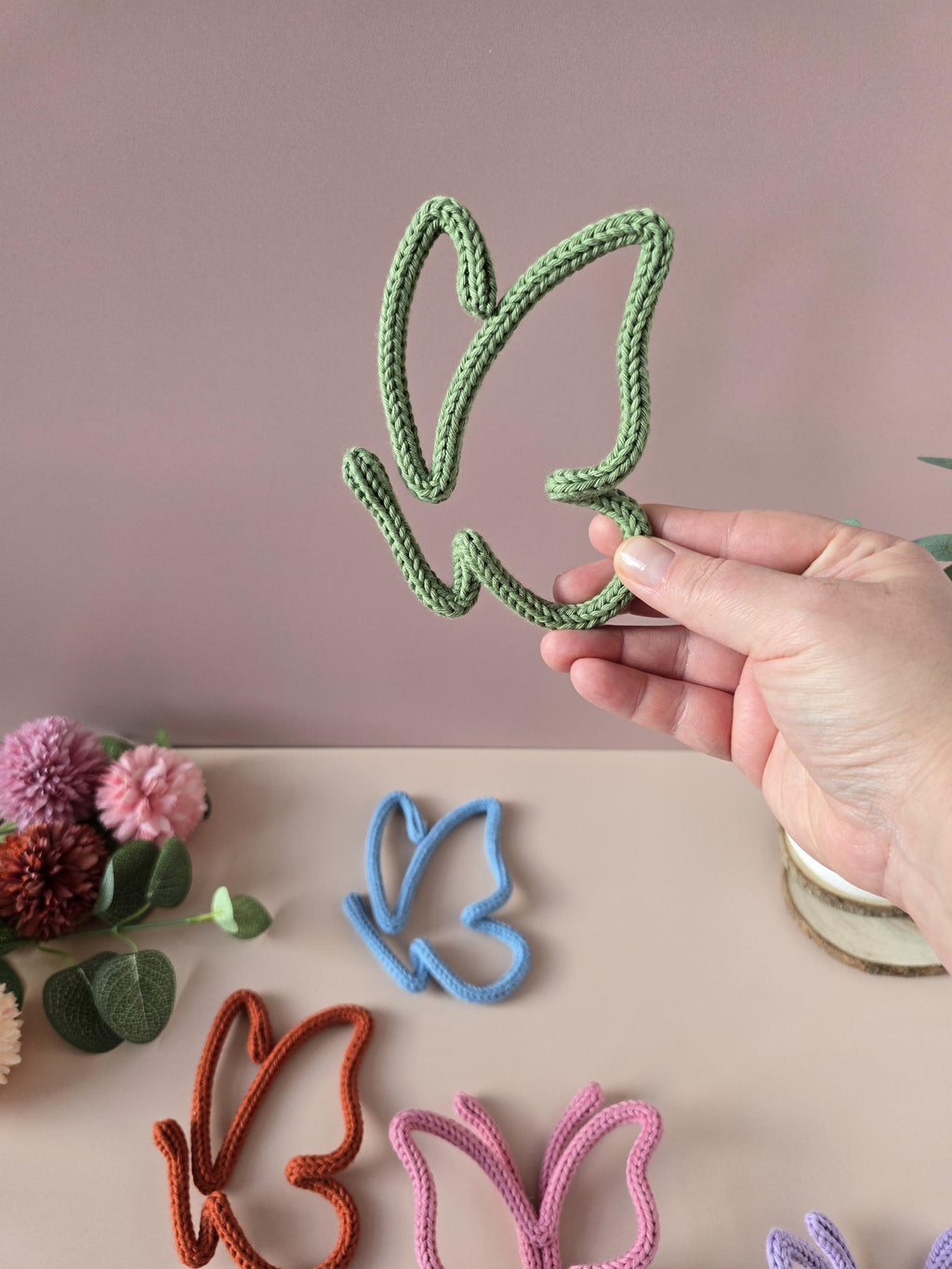 Handmade knitted wire butterfly shown by hand for size reference