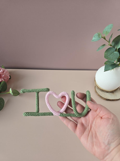 Close-up of handmade knitted wire I Love You sign