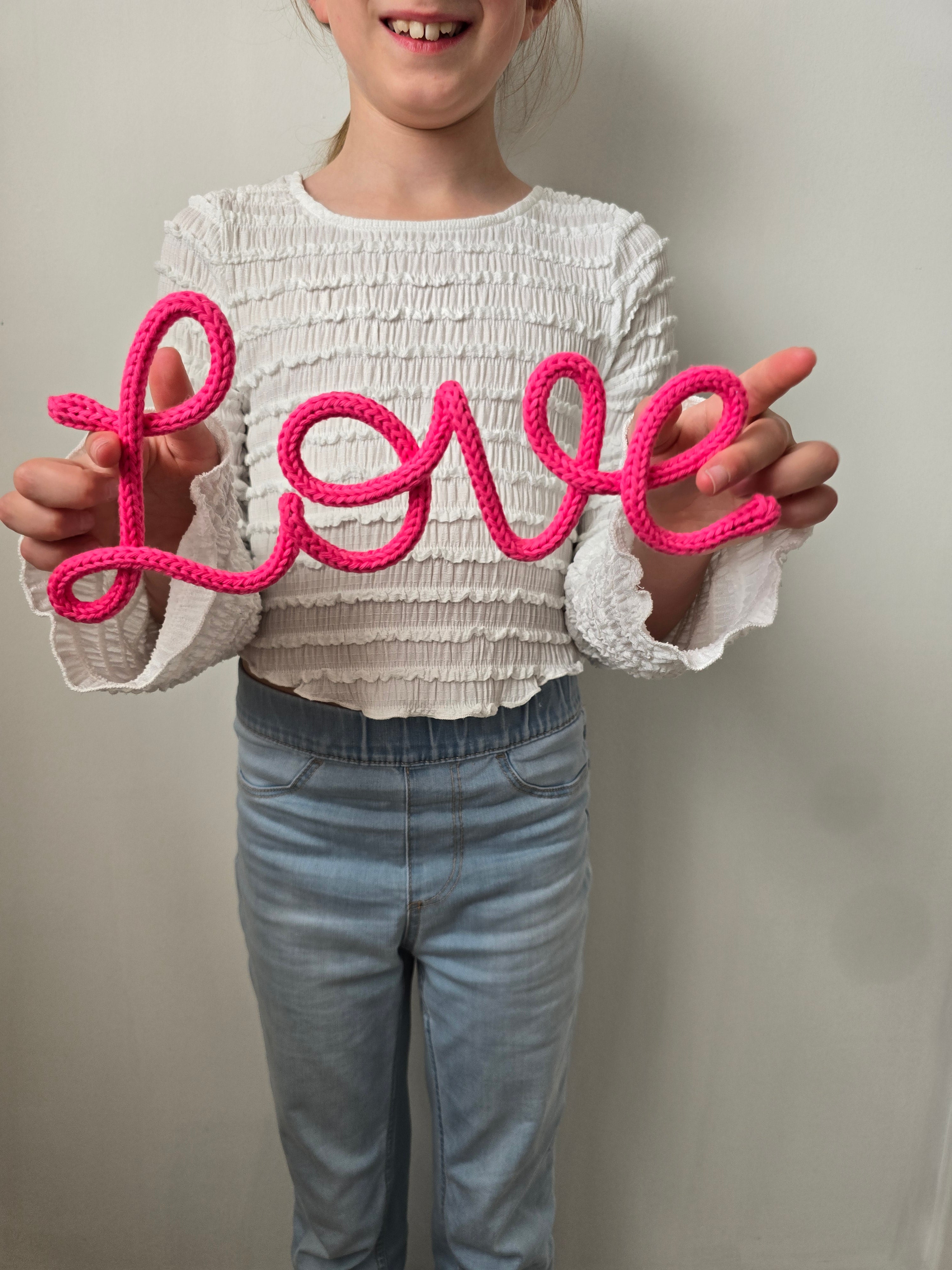 Love knitted wire sign hold by a child