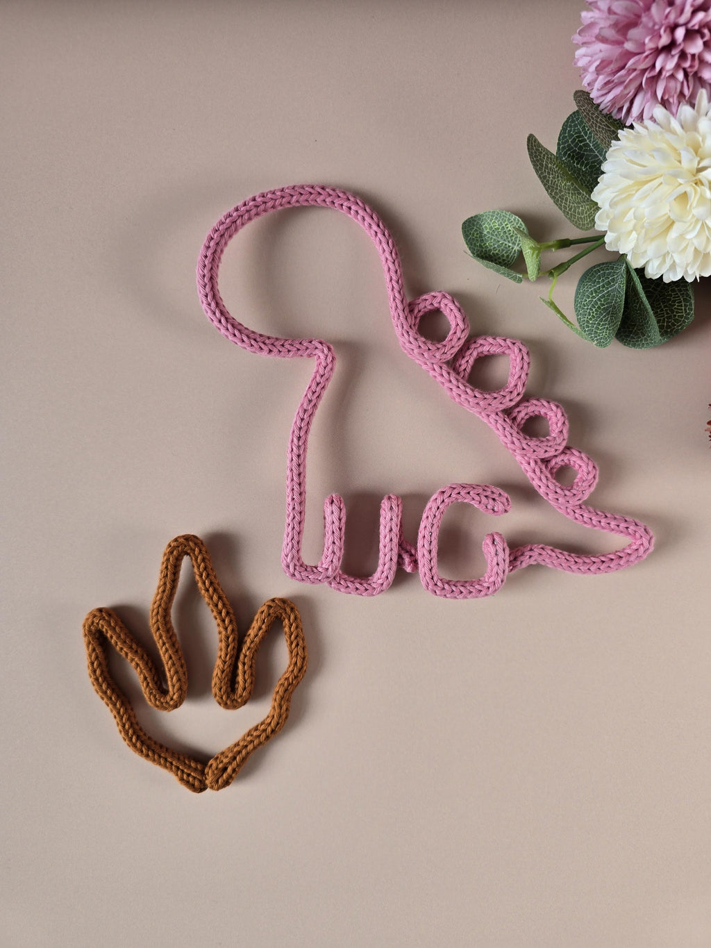 Handmade knitted wire dinosaur wall decor in pink with dino paw