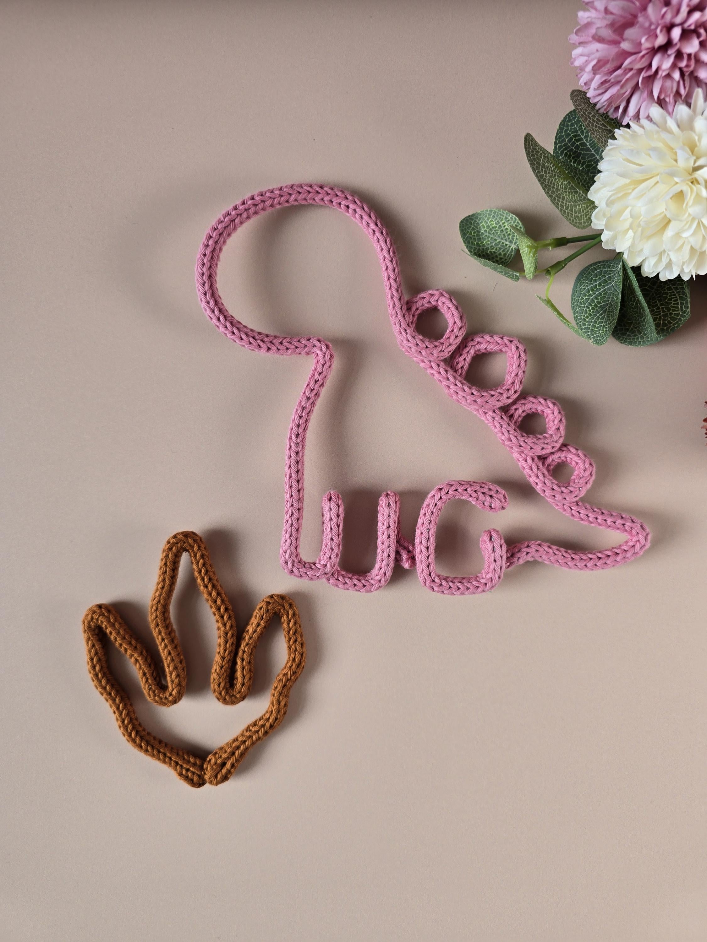 Handmade knitted wire dinosaur wall decor in pink with dino paw