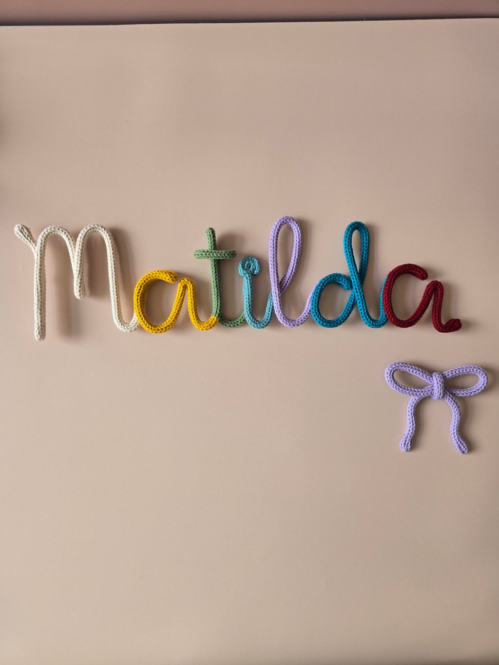 Signature multicoloured personalised name sign with handmade flower and moon details for a nursery or reading corner.