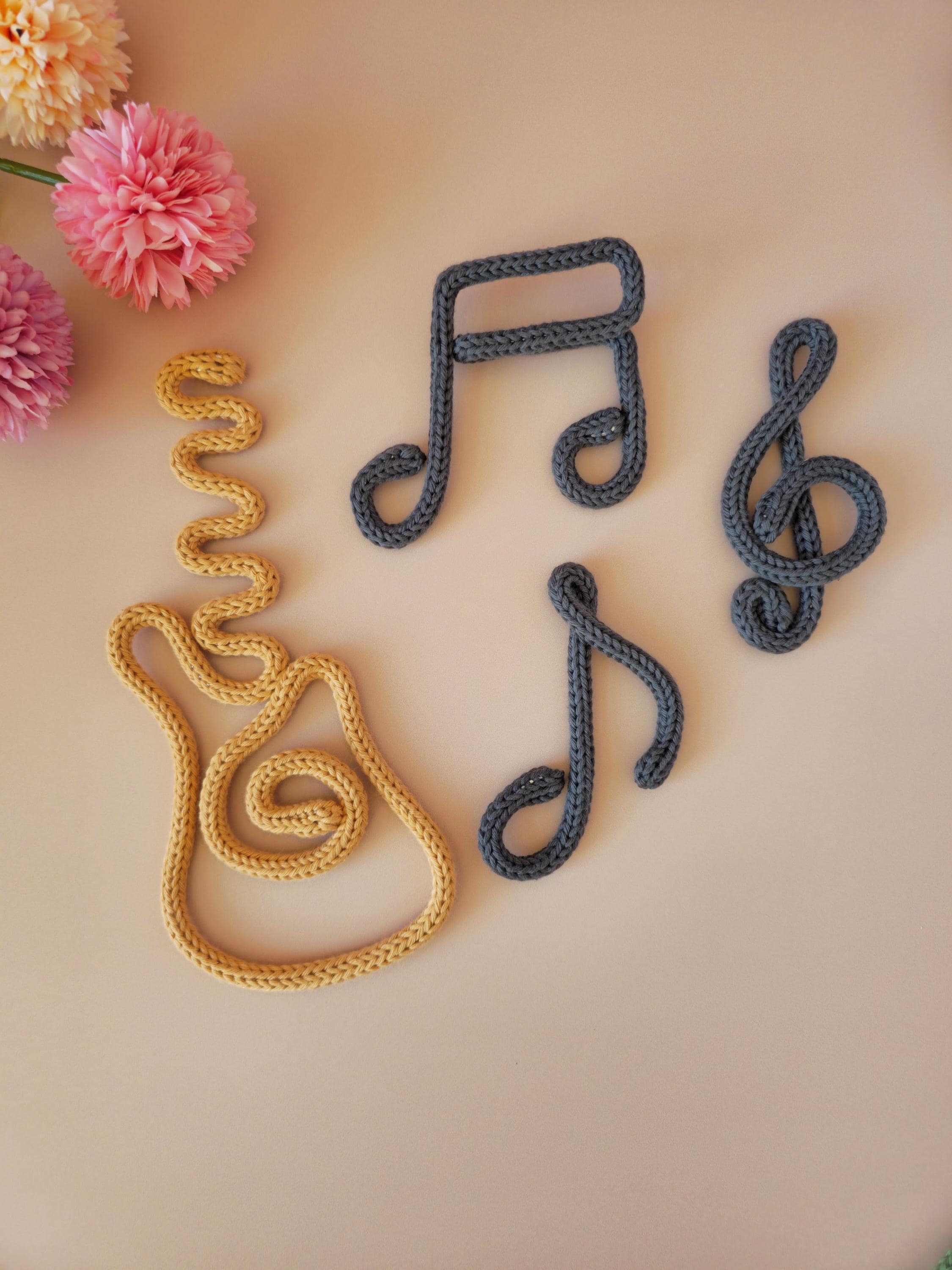 Handmade knitted wire treble clef wall decor in cotton yarn, ideal for music-themed nursery or bedroom decor.