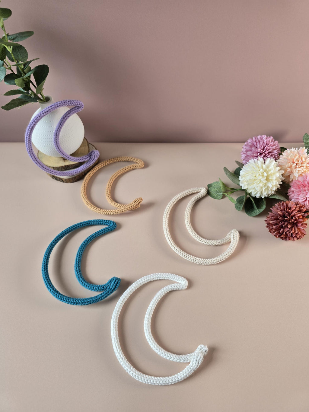 Knitted wire moon decorations shown in different colours