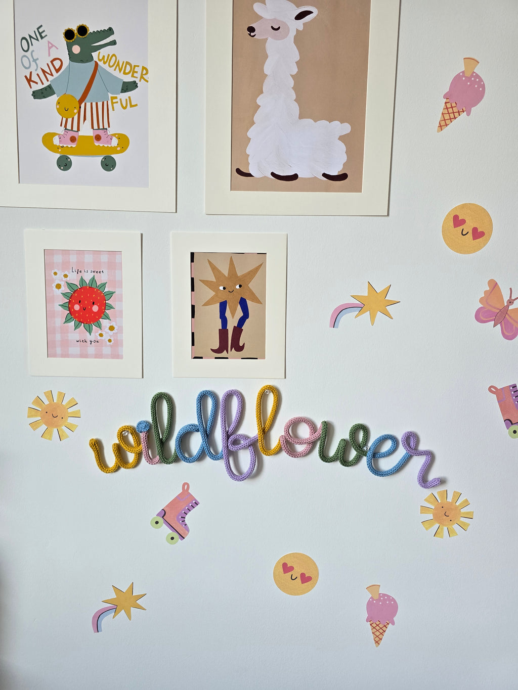 Multicolour Wildflower knitted-wire wall word displayed on a children’s gallery wall with cheerful floral decorations.