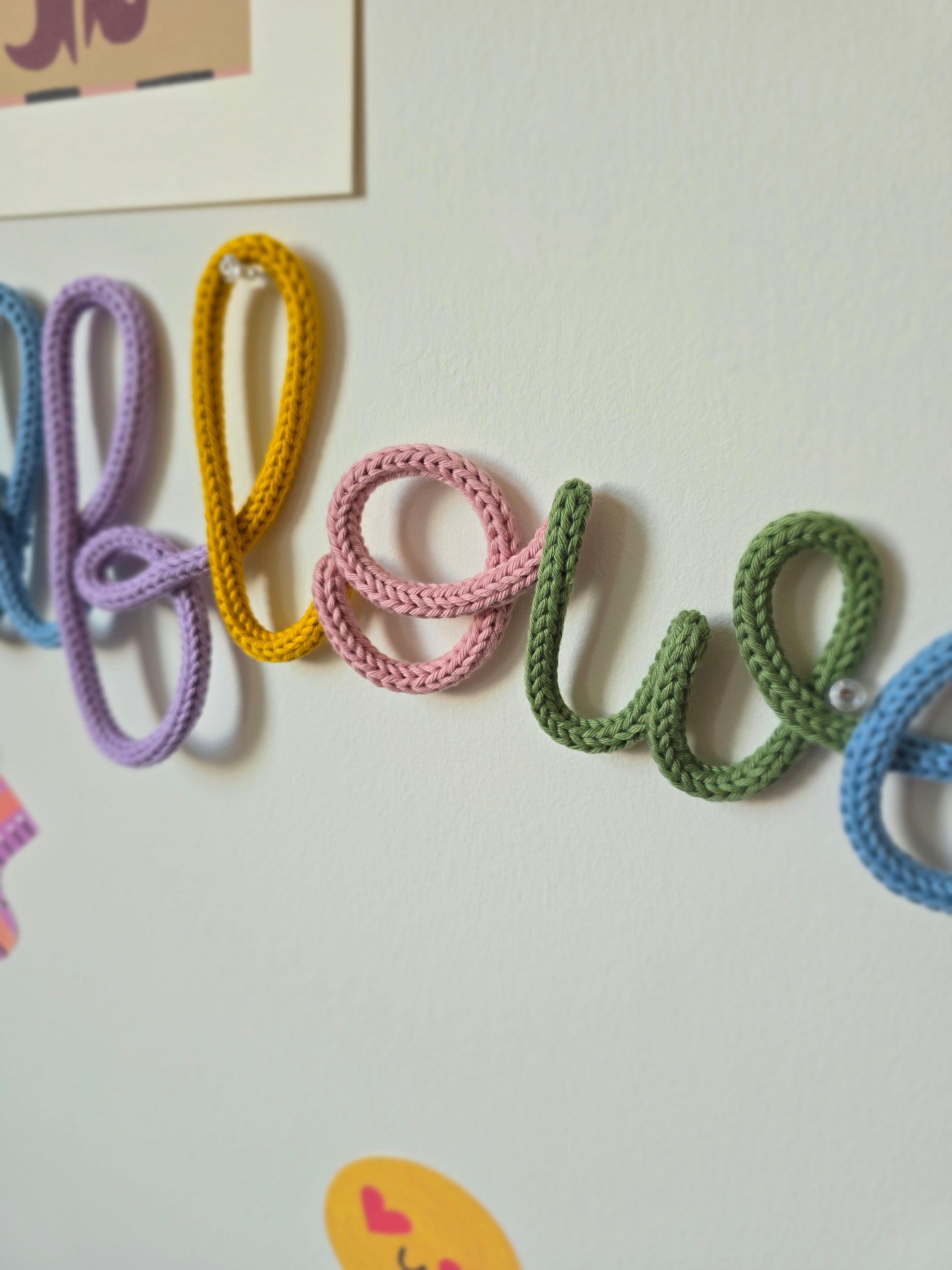 Close-up of the multicolour Wildflower wall word showing the soft knitted cord and handmade lettering.