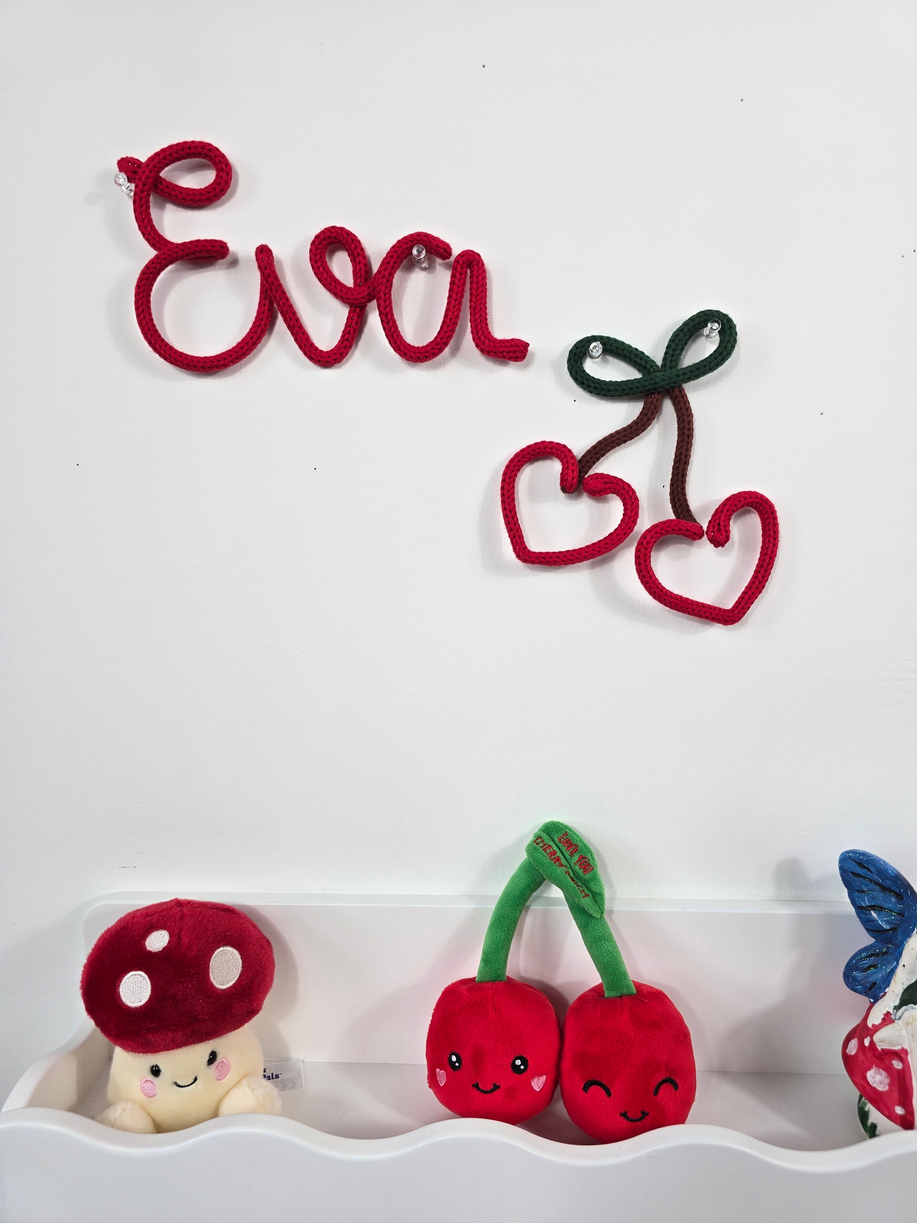 Handmade knitted wire sign saying Eva paired with heart cherry in nursery display