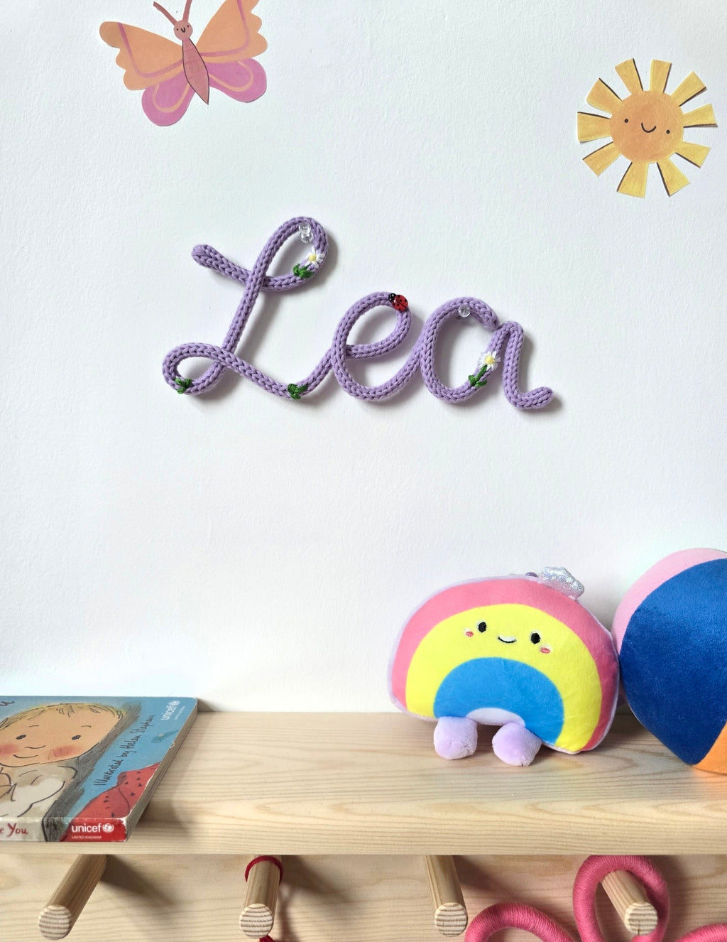 Lilac Lea embroidered knitted wire name sign in Meadow style above a wooden shelf