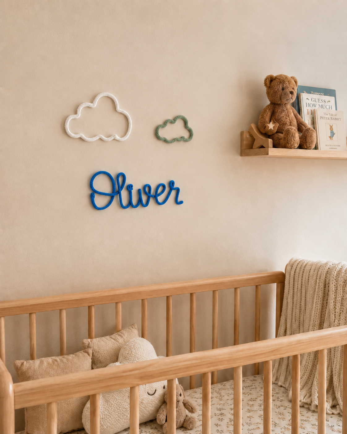 Nursery room with wooden crib, teddy bear, and decorative name sign on wall.
