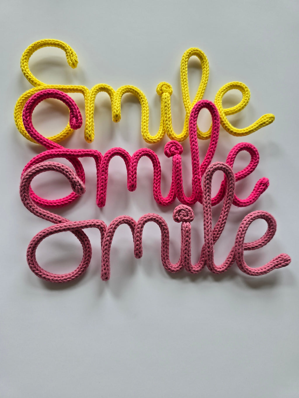 Smile knitted wire sign in yellow, girly pink and pink berry colour