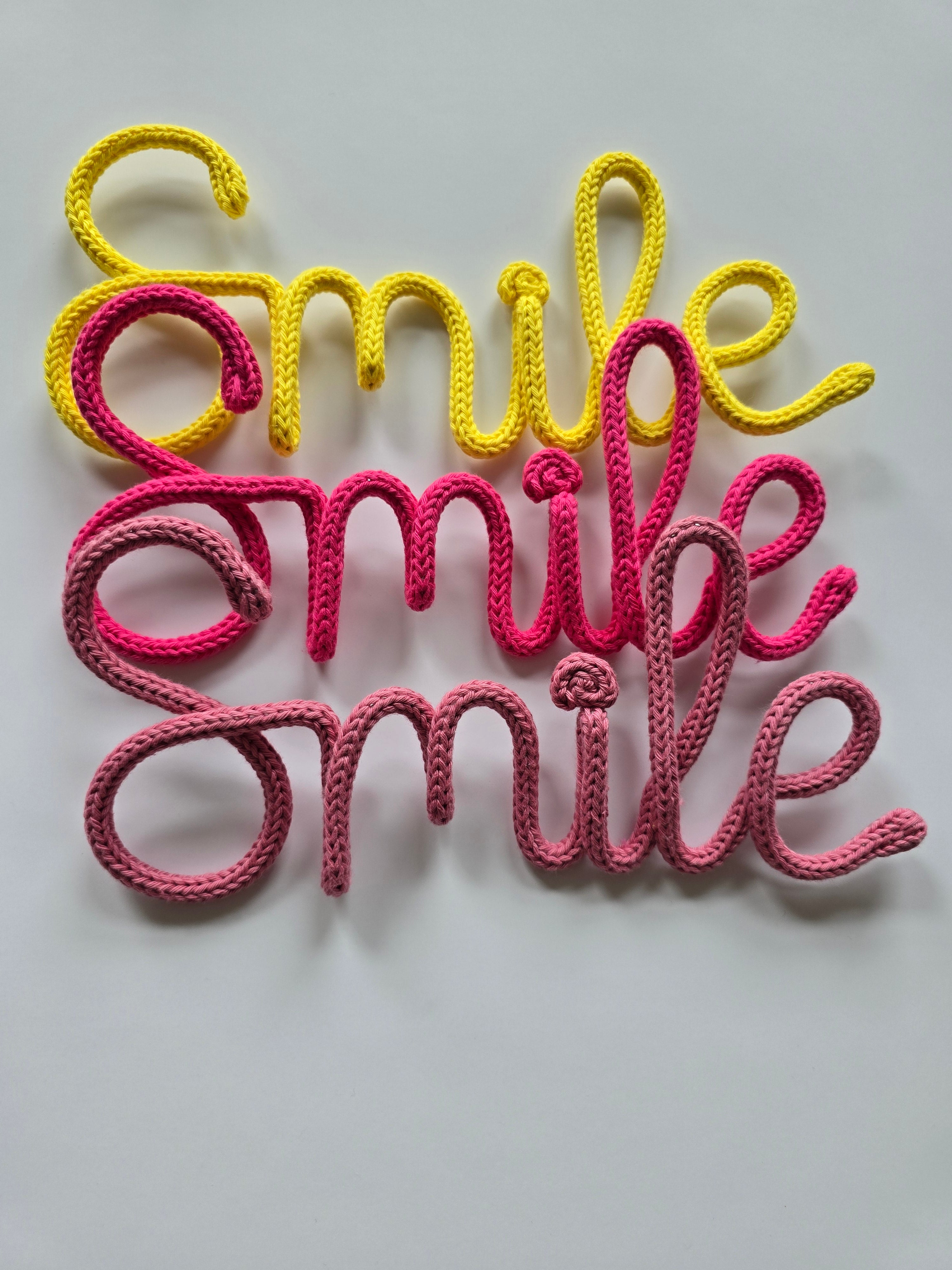 Smile knitted wire sign in yellow, girly pink and pink berry colour