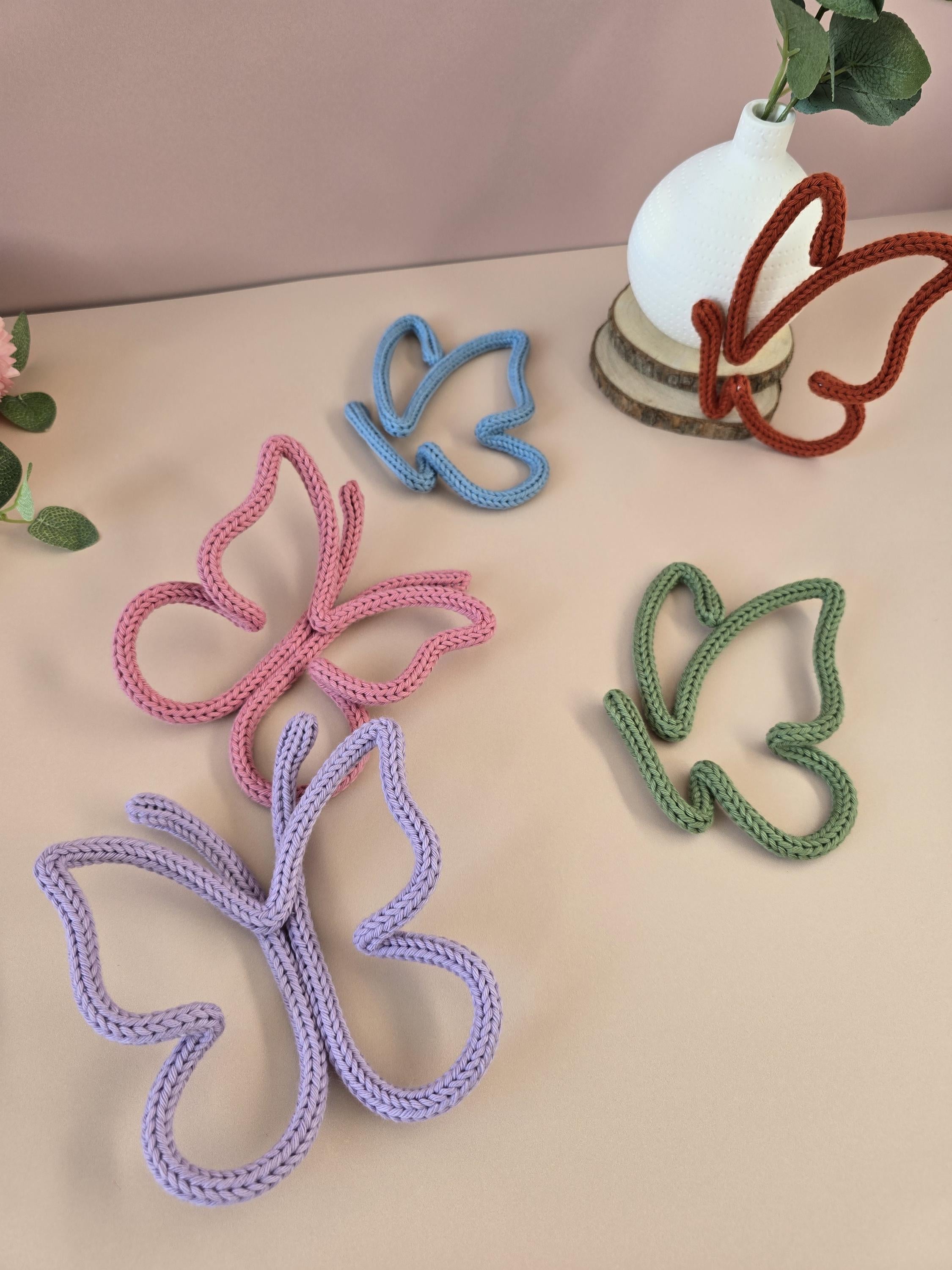 Butterfly-shaped rope toys in various colors on a beige surface.