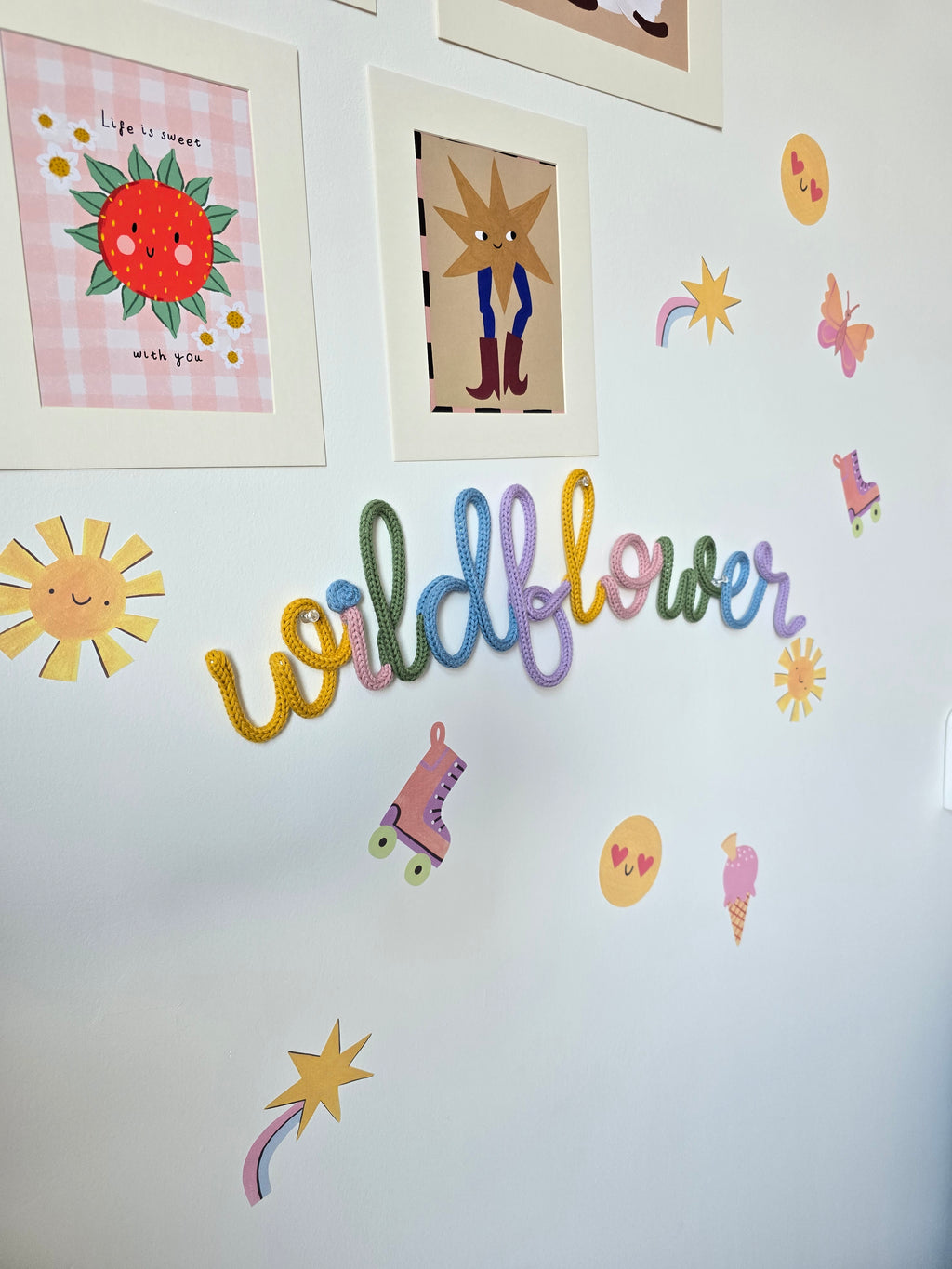 Wildflower knitted-wire wall décor in mustard, pink, green, blue and lilac on a playful children’s bedroom wall.