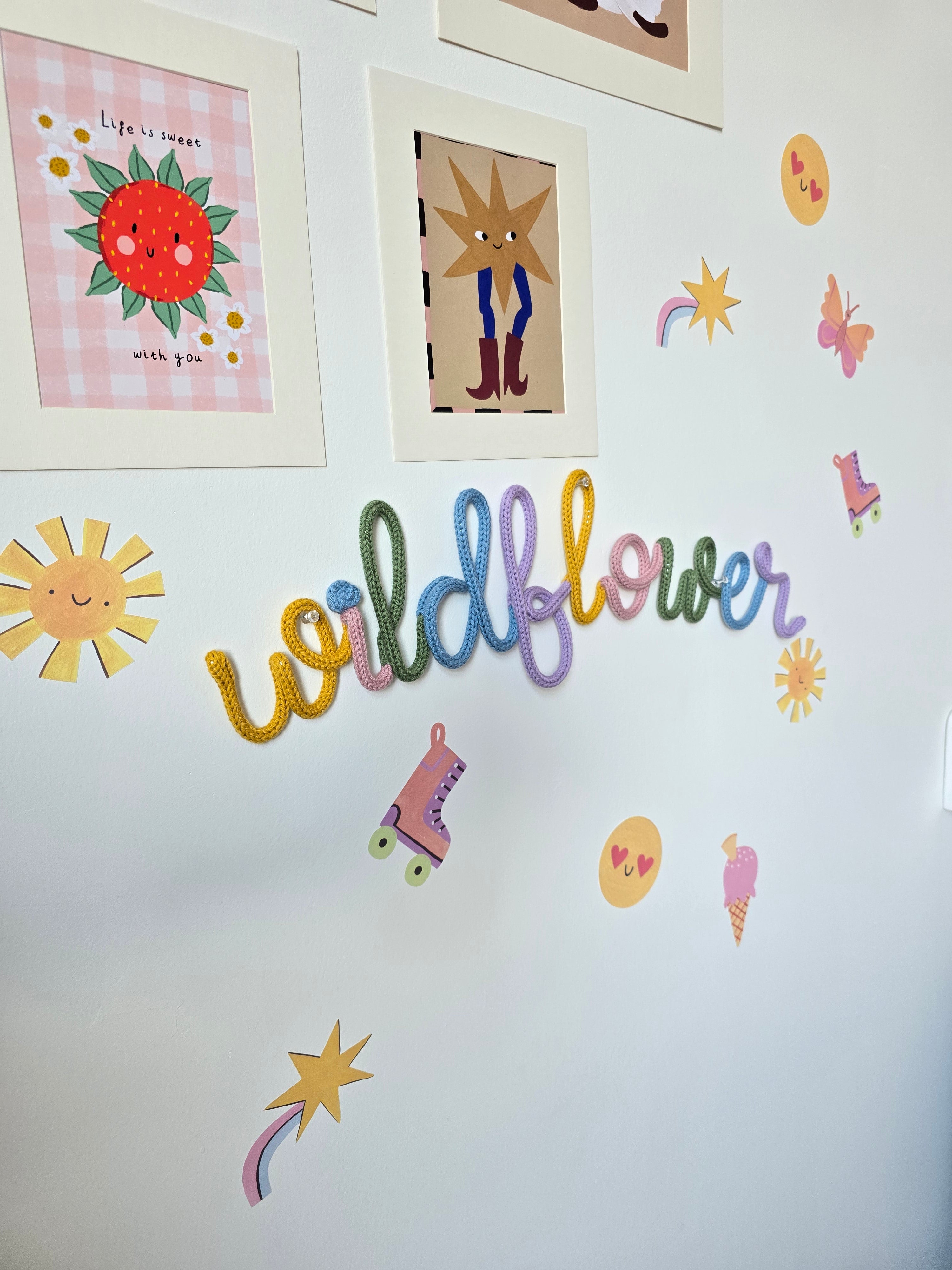 Wildflower knitted-wire wall décor in mustard, pink, green, blue and lilac on a playful children’s bedroom wall.