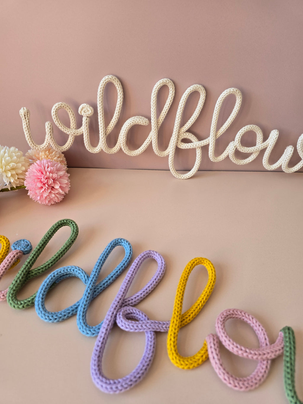 Close-up of the cream and multicolour Wildflower knitted-wire wall word options.