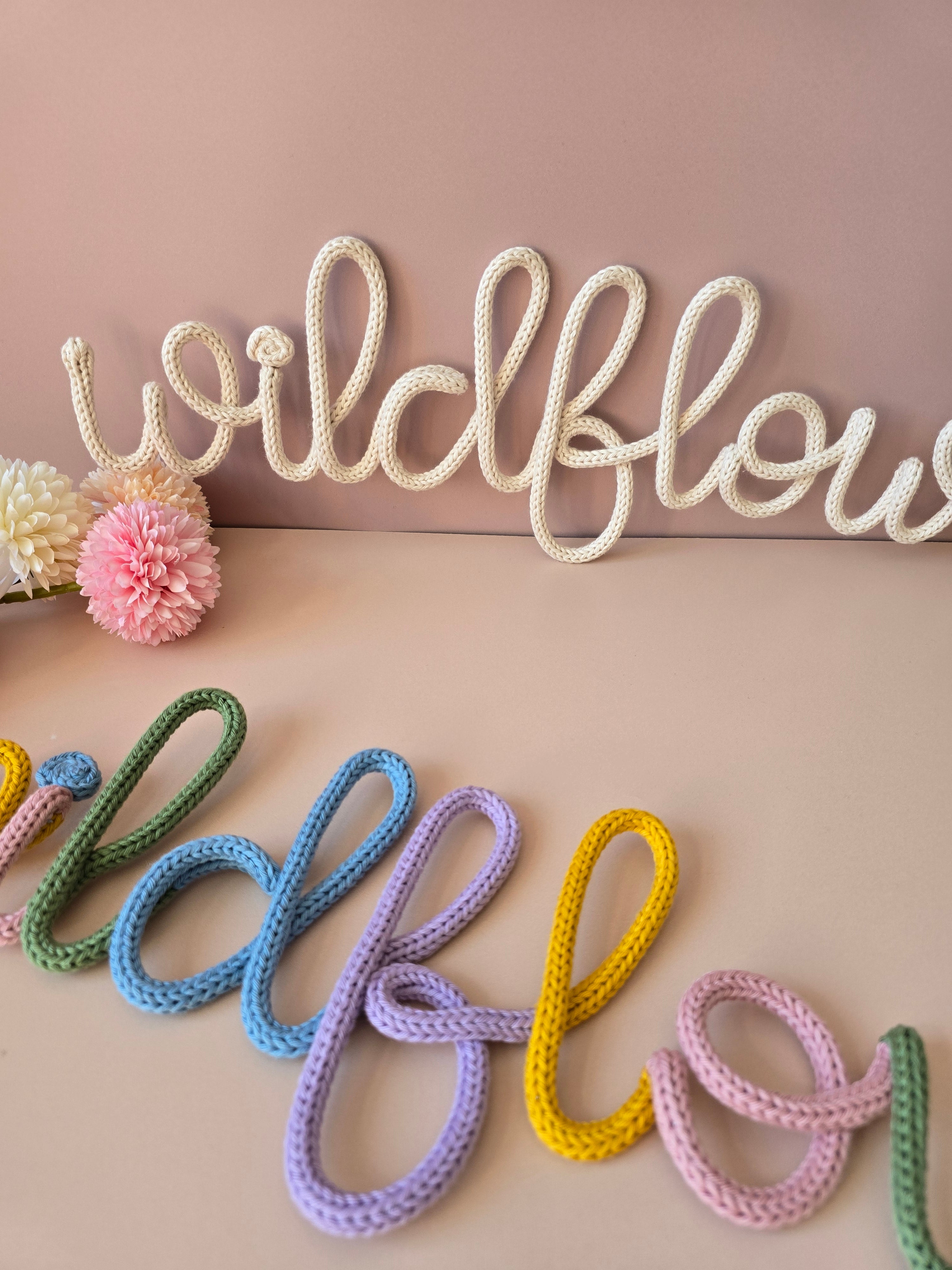 Close-up of the cream and multicolour Wildflower knitted-wire wall word options.